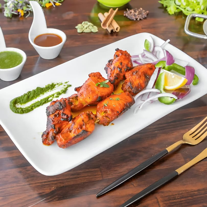 Star of India's Indian chicken tikka, garnished with onions, peppers, and lemon, with green and brown sauces.