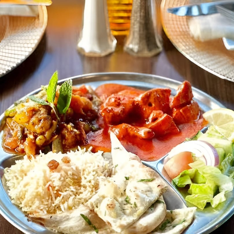 A Star of India thali with chicken tikka masala, vegetable curry, rice, naan, and salad.